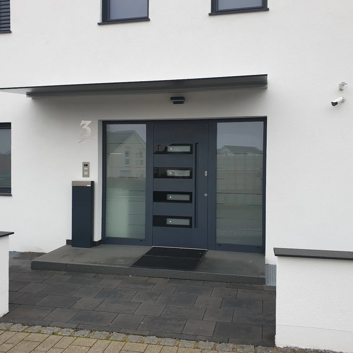 Anthrazit-Haustür mit Seitenteilen und Glasausschnitten am modernen Neubau