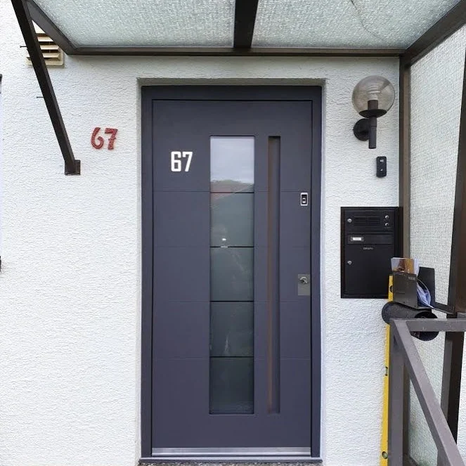 Graue Haustür mittigem Lichtausschnitt unter Glasvordach
