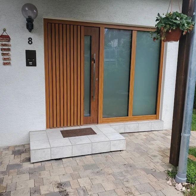 Holz-Haustür in kräftigem Teak-/Eichenton mit senkrechtem Lamellen-Design über die ganze Breite