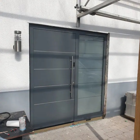 Dunkle Haustür mit waagerechten Linien unter Glasvordach