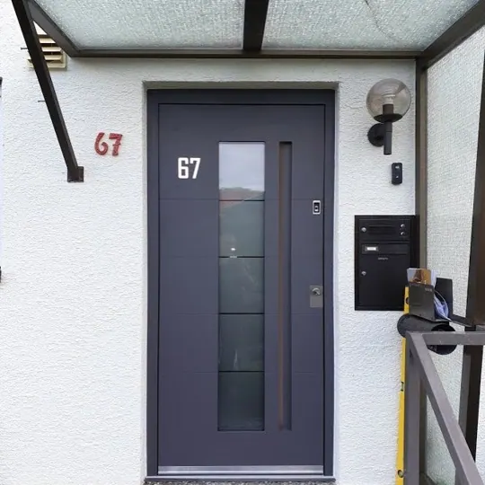 Graue Haustür mittigem Lichtausschnitt unter Glasvordach