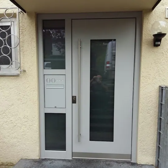 Hellgraue Haustür mit integriertem Briefkasten und Glasstreifen