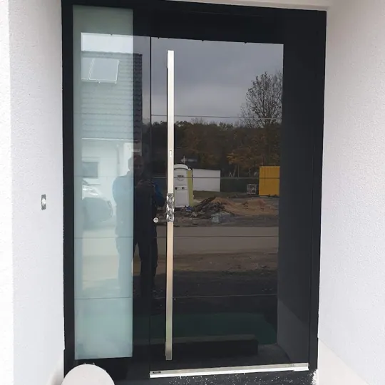 Schwarze Ganzglas-Haustür mit Seitenteil im Neubau