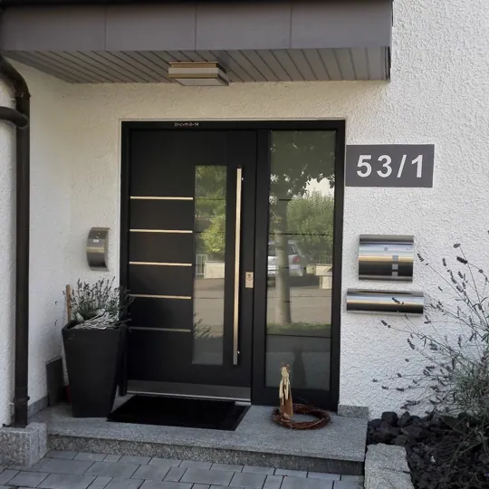 Schwarze Haustür mit Edelstahl-Linien und Seitenteil