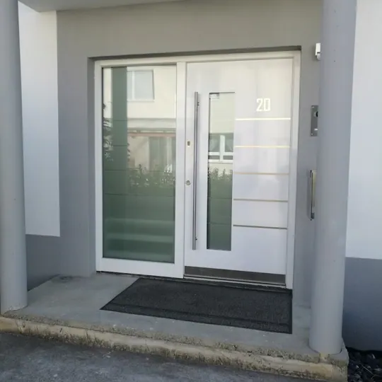 Weiße Haustür mit Edelstahl-Linien und großem Seitenteil