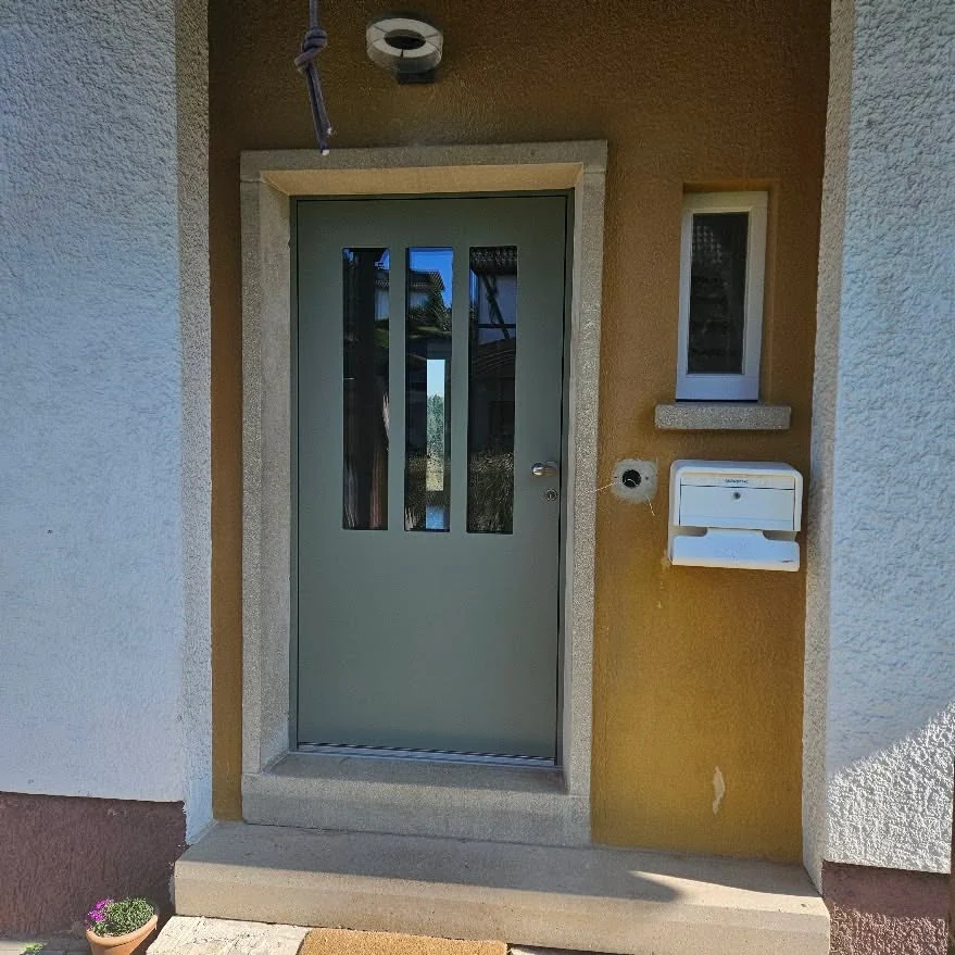 Zementgraue Haustür mit drei Glasstreifen im Altbau
